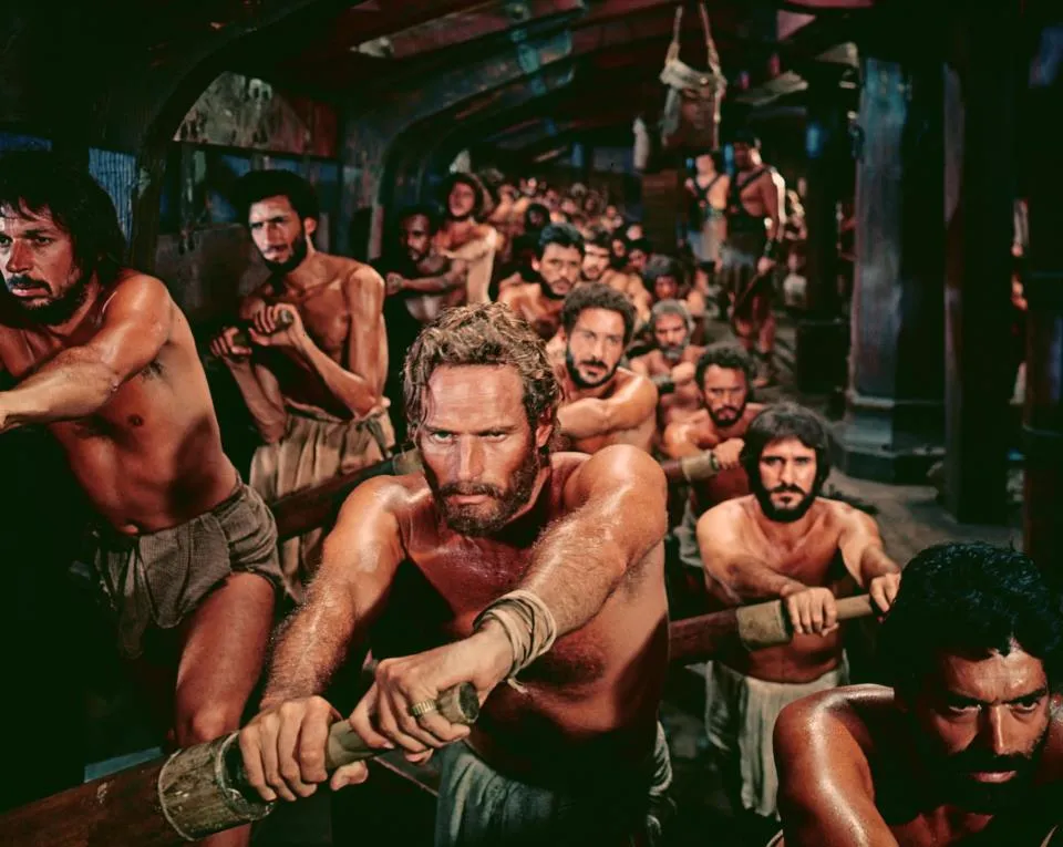 A scene from the 1959 film Ben-Hur in which Charlton Heston in the title role is one of a large group of slaves forced to row a Roman galley.